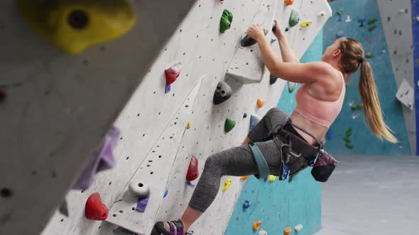 Caucasian woman wearing face mask climbing wall at indoor climbing wall