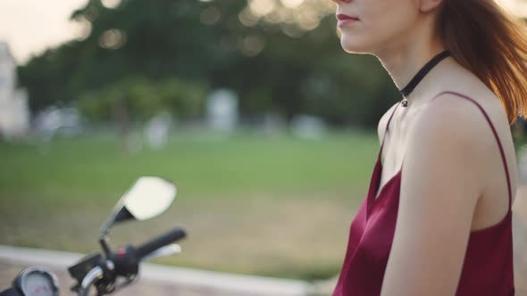 Beautiful Young Redhaired Woman Motorcyclist with Her Motorcycle and Helmet