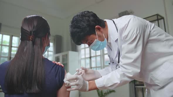 Doctor In Safety Gloves And Protective Mask Is Making A Vaccine Injection To A Female Patient