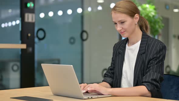 Cheerful Young Businesswoman with Laptop Smiling at Camera