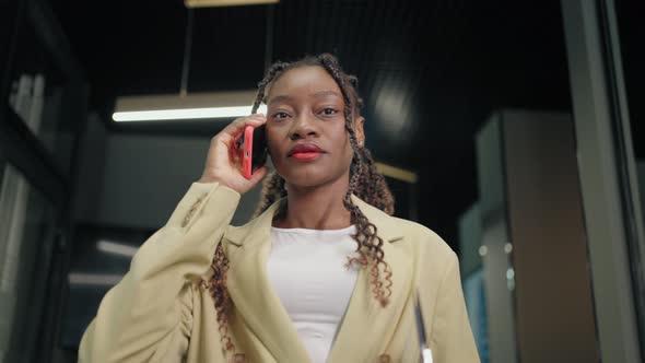 Portrait of a Black Business Woman Walking Down the Corridor of a Business Center Talking on the