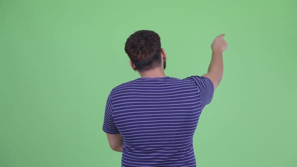 Rear View of Young Overweight Bearded Indian Man Pointing Finger