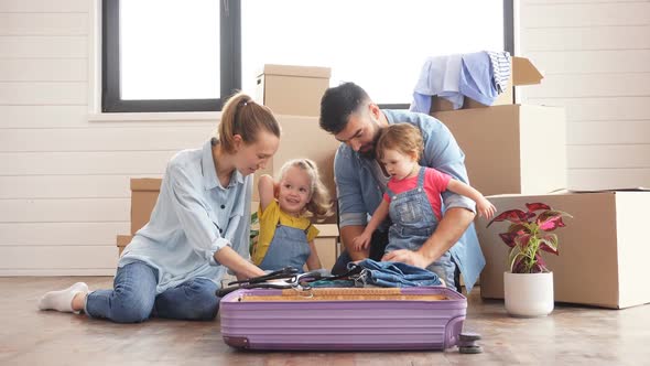 Happy Caucasian Family Sit on Floor Unpack Suitcase in New House