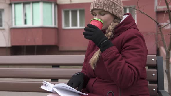 A Young Mother Reads a Book in the Fresh Air and Sips Aromatic Tea