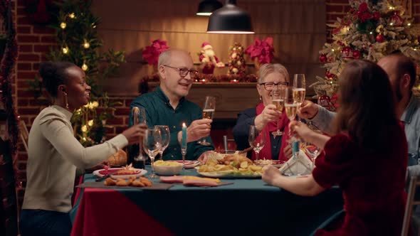 Happy Close Family Members Clinking Champagne Glasses While Sitting Together at Christmas Dinner