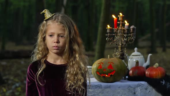 Portrait of Cute Sad Lonely Little Girl Standing in Forest on Halloween Alone