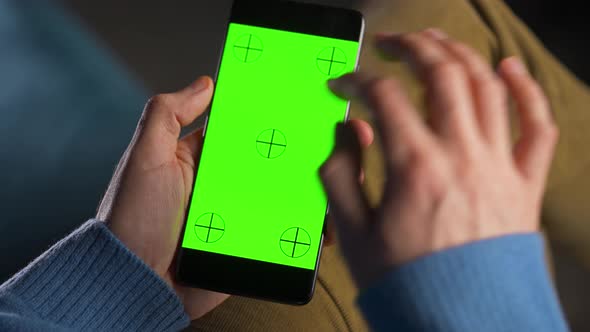 Man Using Smartphone with Green Mockup Screen in Vertical Mode