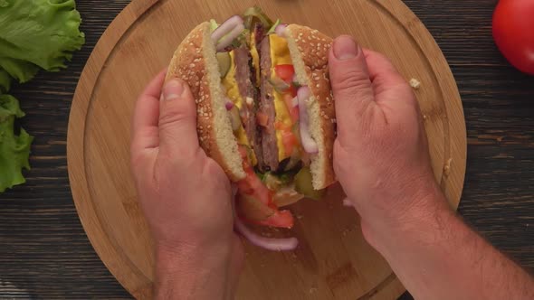 Top View of the Male Hands Opening Burger with Meat Cutlet Cut in Two Halves