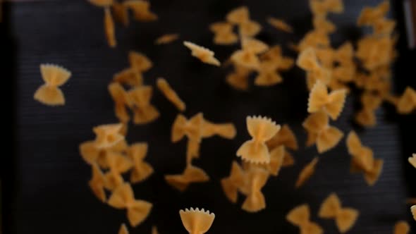 Farfalle pasta flying up and hanging in the air on a black background