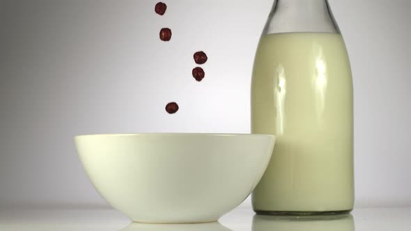 Chocolate Balls Falling In A White Dish Near A Milk On A Table