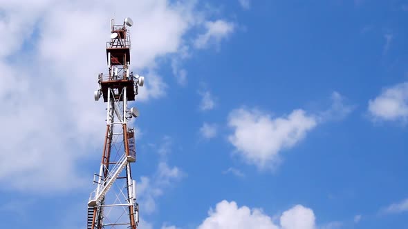 Telecommunication Tower With Antennas And Repeaters Against Blue Sky And Clouds