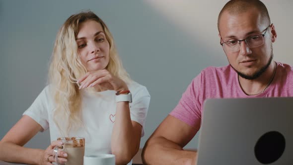 Young couple working together in coffee shop with laptop  browsing online.