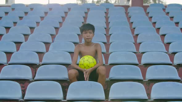 Boy Sitting At The Stadium With A Ball