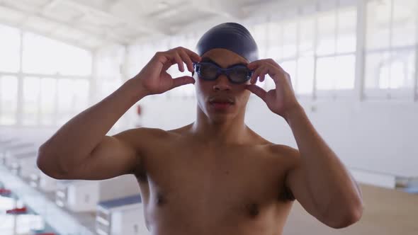 Swimmer taking off his pool goggles and looking at camera