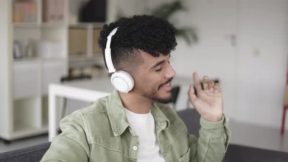 Young Latino Man Listening Music with Headphones While Dancing at Home