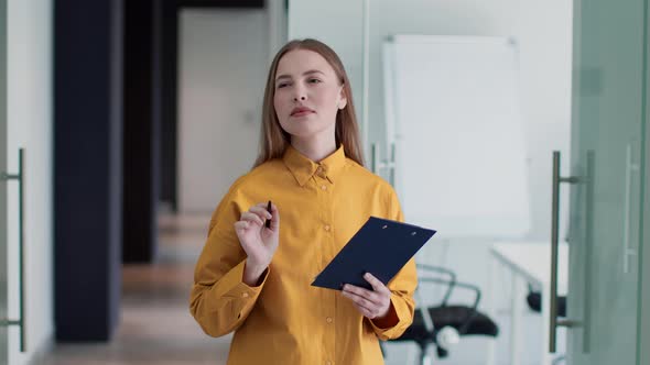 Young Concentrated Professional Woman Manager Making Stocktaking at Office Writing Notes in Notepad