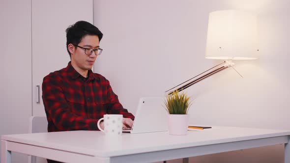 Asian Man with Glasses Working on the Laptop