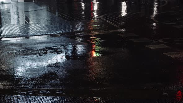 Drizzle Puddles and Night Urban Lights Reflecting on the Road
