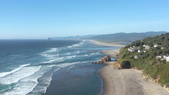 Aerial slow flying above relaxing beach and luxurious retirement vacation houses built on the cliff.