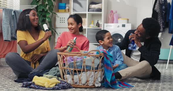 A Family Sits on the Laundry Room Floor Sorting Clothes Before Putting Them in the Washing Machine