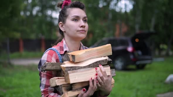 A young woman carries an armful of firewood in the village. Household woman