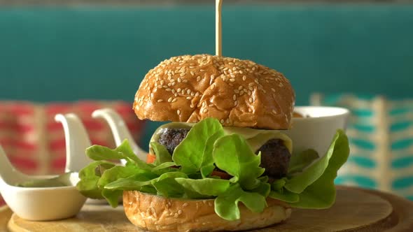 Rotate Homemade Burger with Fried Potatoes and Sauces on a Wooden Tray