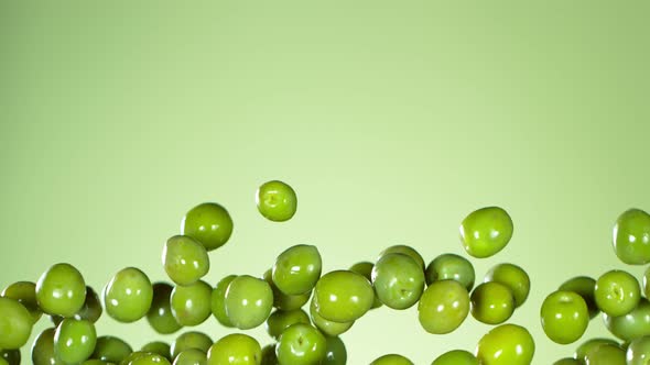 Super Slow Motion Shot of Flying Fresh Green Olives on Light Green Gradient Background at 1000 Fps.