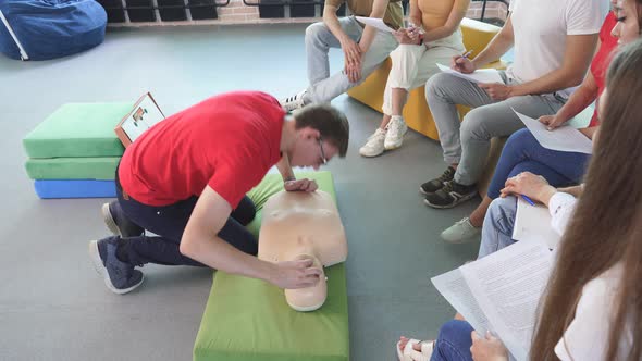 CPR Class with Young Caucasian Instructors Speaking and Demonstrating Help First Aid