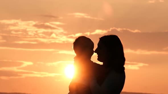 Silhouette of a Mother Kissing Her Son at Sunset