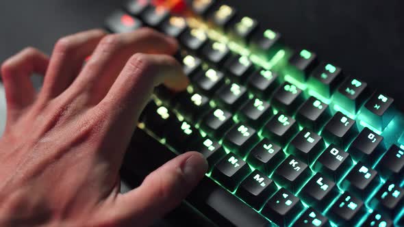 Young Gamer Plays a Video Game Closeup of Hands on the Keyboard Illuminated Multicolor Neon