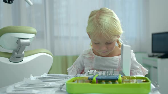 Little Girl Looks at Dental Instruments in Cabinet