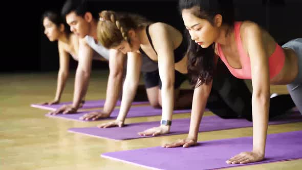 Group of Asian Women and Man Doing Pushup Exercises on Yoga Mats in Aerobics Class at Gym Club