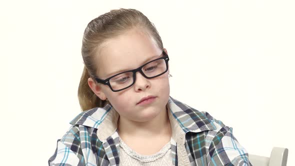 Little Girl Sits and Writes That His Notebook. White Background. Close Up