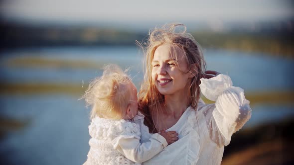 Smiling Woman Holding Her Baby While Standing at Nature and Looking at the River