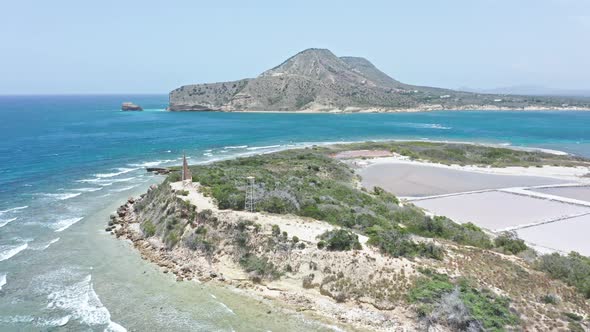 Aerial view of small islet - Isla Cabra lighthouse structure and salt pans