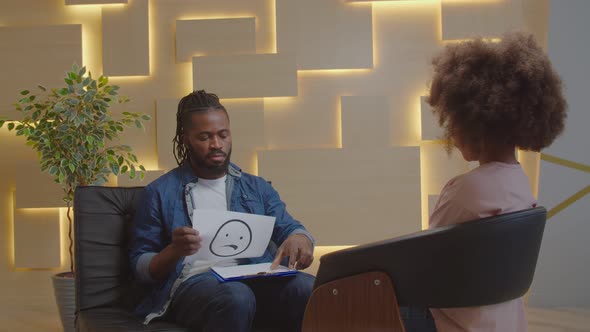 African Male Psychologist Doing Psychotherapy with Child Using Emotion Cards