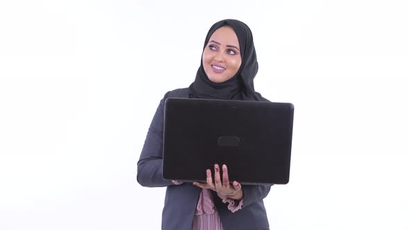 Happy Young African Muslim Businesswoman Thinking While Using Laptop