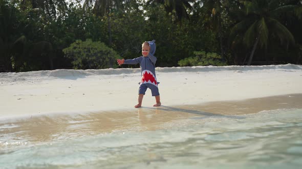 The Kid Cheerfully Runs Along the Shore and Watches As the Wave Washes His Feet