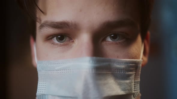 Portrait of Young Man with Light Blue Eyes Wearing Medical Protective Mask for Prevention