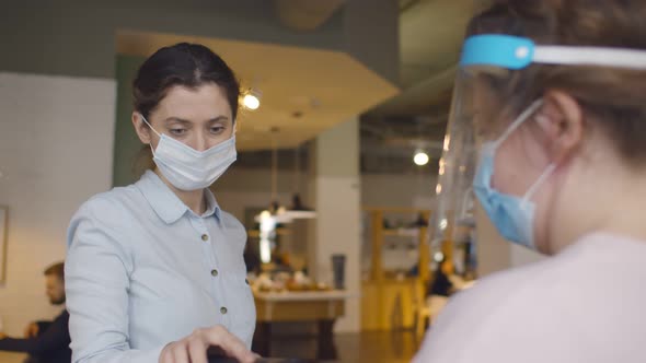 Young Woman in Safety Mask Paying with Contactless App on Smartphone for Takeaway Order in Cafe