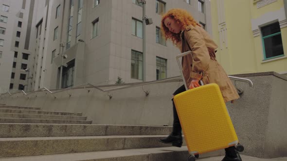 Young European Woman Enters the Business Center with a Yellow Suitcase