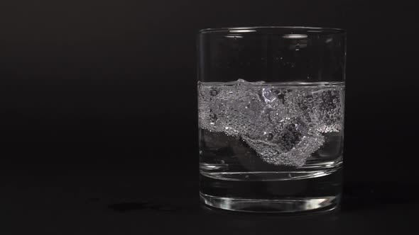 Close-up of carbonated transparent clear water mixed in a glass with ice cubes 