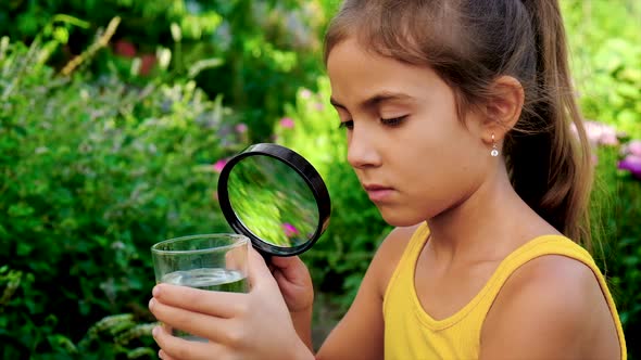 The Child Examines the Water Through a Magnifying Glass