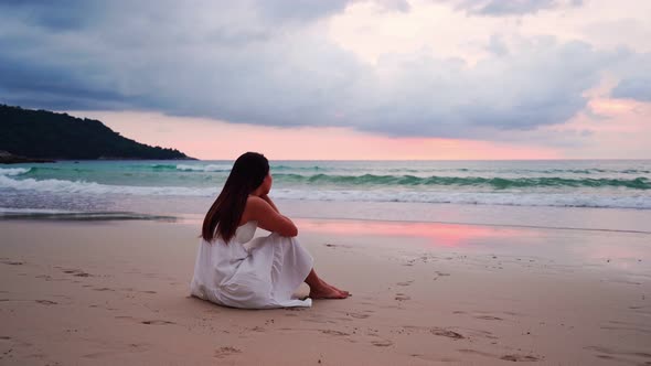 Young woman feeling lonely and sad looking at the sea on a gloomy day