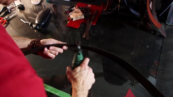 Leather Workshop  a Man Grinds the Edges of a Belt Using a Tool