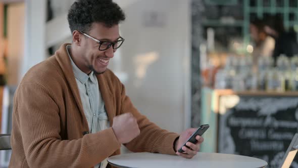 African Man Celebrating Success While Using Smartphone