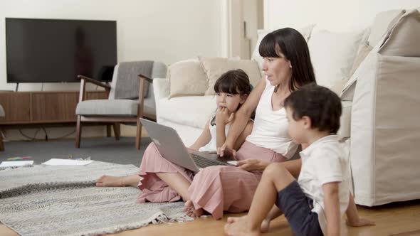 Mom Showing Content on Laptop To Two Kids