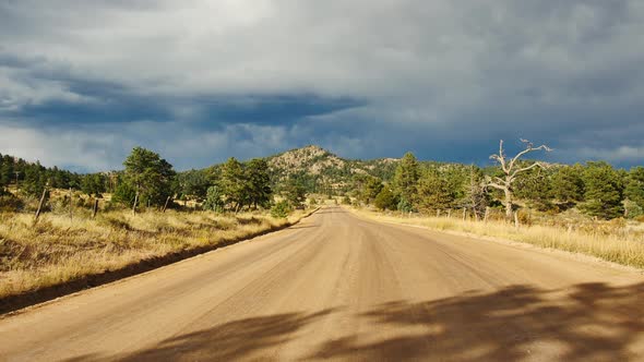 A dirt road in the Colorado countryside as storm clouds start to roll in