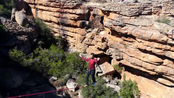 Male highliner walkng on a rope over rocky mountains 4k