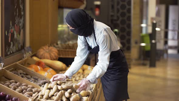 Woman in Niqab Refill the Potatos on the Stock at the Supermarket